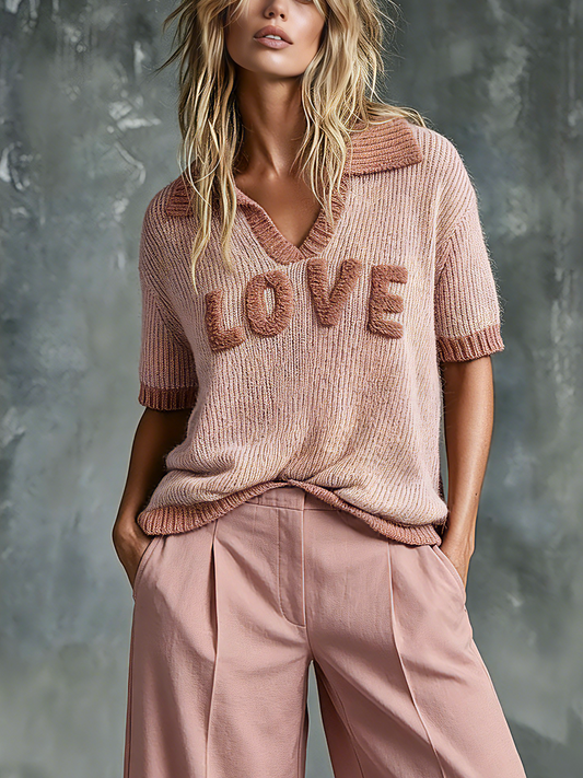 Woman wearing a pink 'LOVE' sweater against a textured gray background