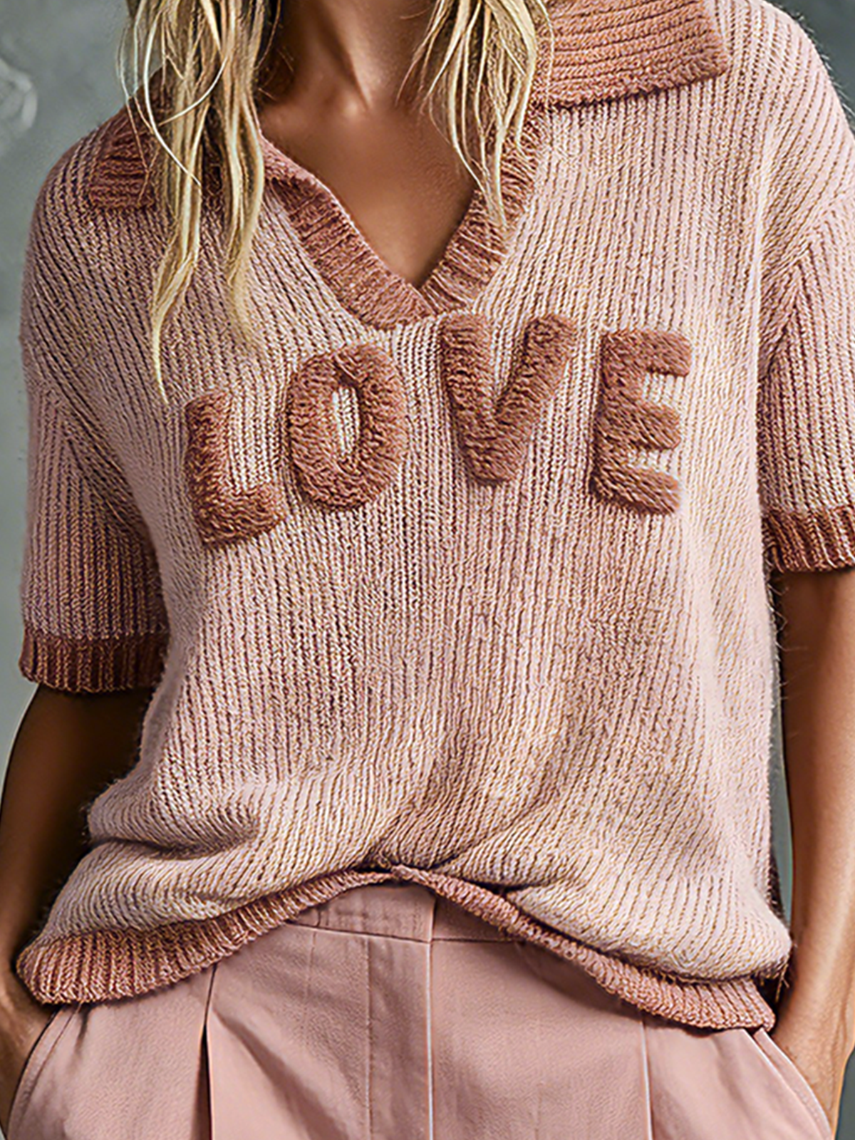 Pink knit sweater with 'LOVE' text worn by a person