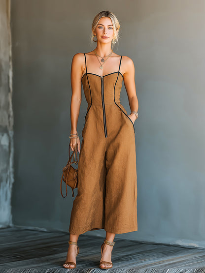 Woman wearing a brown jumpsuit with black accents, standing against a neutral background.