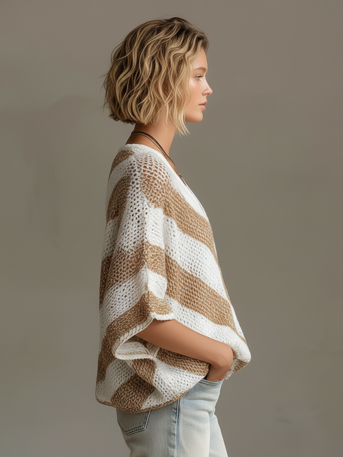 Woman wearing a striped poncho against a plain background