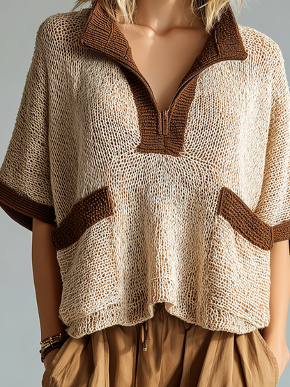 Knitted poncho with brown trim worn by a mannequin against a neutral background