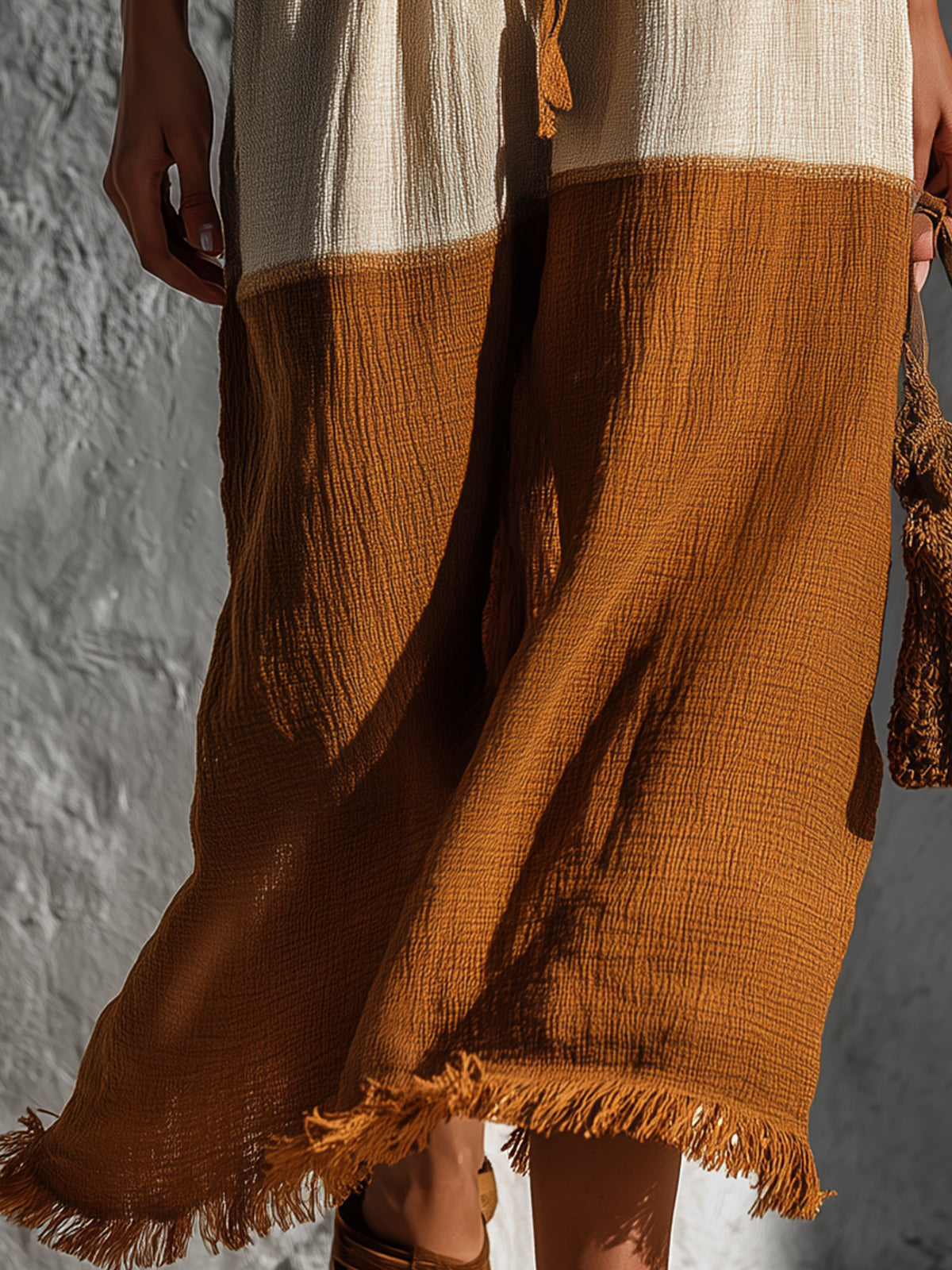 Brown and beige fabric with frayed edges against a textured wall.
