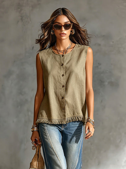 Woman wearing a sleeveless olive green top and blue jeans against a gray background