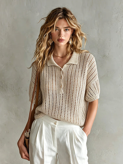 Woman wearing a beige knitted top and white pants against a gray background