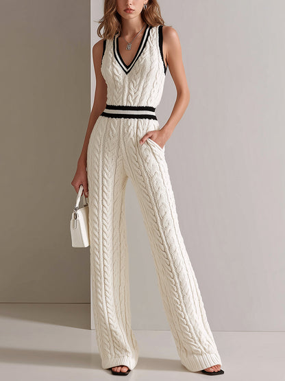 Woman wearing a white cable knit jumpsuit with black accents against a plain background